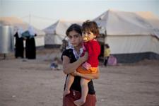 Dans un camp de réfugiés, une jeune fille tient sa petite sœur dans ses bras.