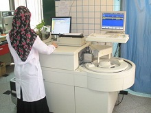 La photo nous montre un technicien de laboratoire en train de travailler sur le système Axsym qui permet de réaliser des tests sérologiques, des dosages hormonaux et de mesurer d'autres paramètres biologiques