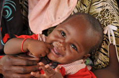 A mother cradles her smiling, healthy baby