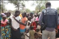 A large group of South Sudanes women and their children with a WHO staff member in the foreground