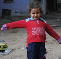 A photograph of a young girl spreading out her arms and smiling at the camera