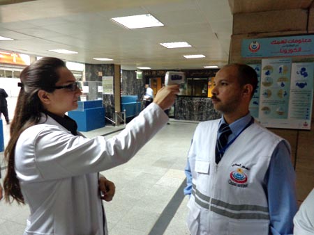 Health staff demonstrate checking the temperature of incoming passengers at Cairo International Airport