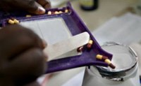 A close up on two hands holding a pills counter tray and a spatula while sorting and loading up pills in a container 