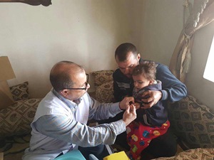 A child in Hawiija receives a measles vaccine from a mobile medical team member