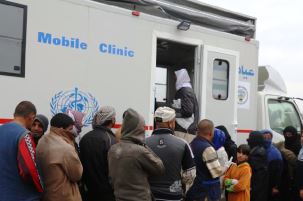 Patients including women and children in Hamam Aleel camp line for services at WHO mobile medical clinic run by WHO implementing partner UMIS