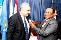 Dr El Bushra places a World Health Day pin on the jacket of the Director General of the Ministry of Public Health 