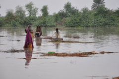 People wade through flood water in Badin, Sindh